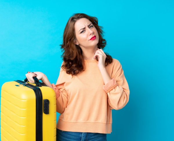 Traveler woman with suitcase over isolated blue background thinking an idea