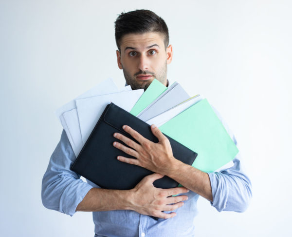 Puzzled office worker holding pile of documents
